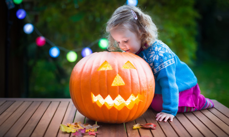 Little Girl Carving Pumpkin At Halloween
