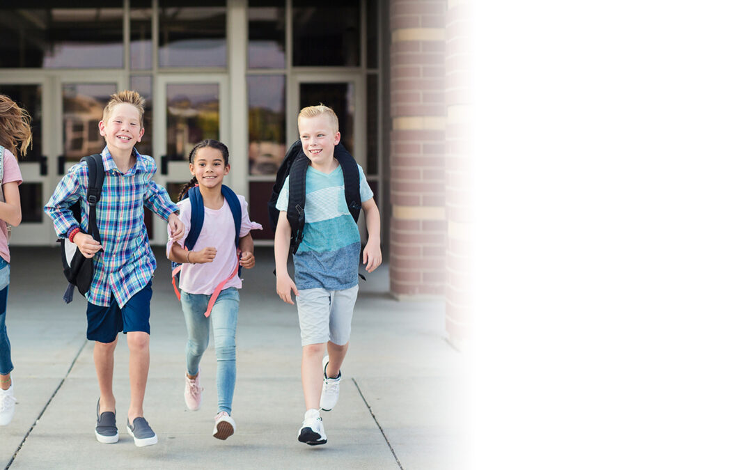 Group of school kids running as they leave elementary school at